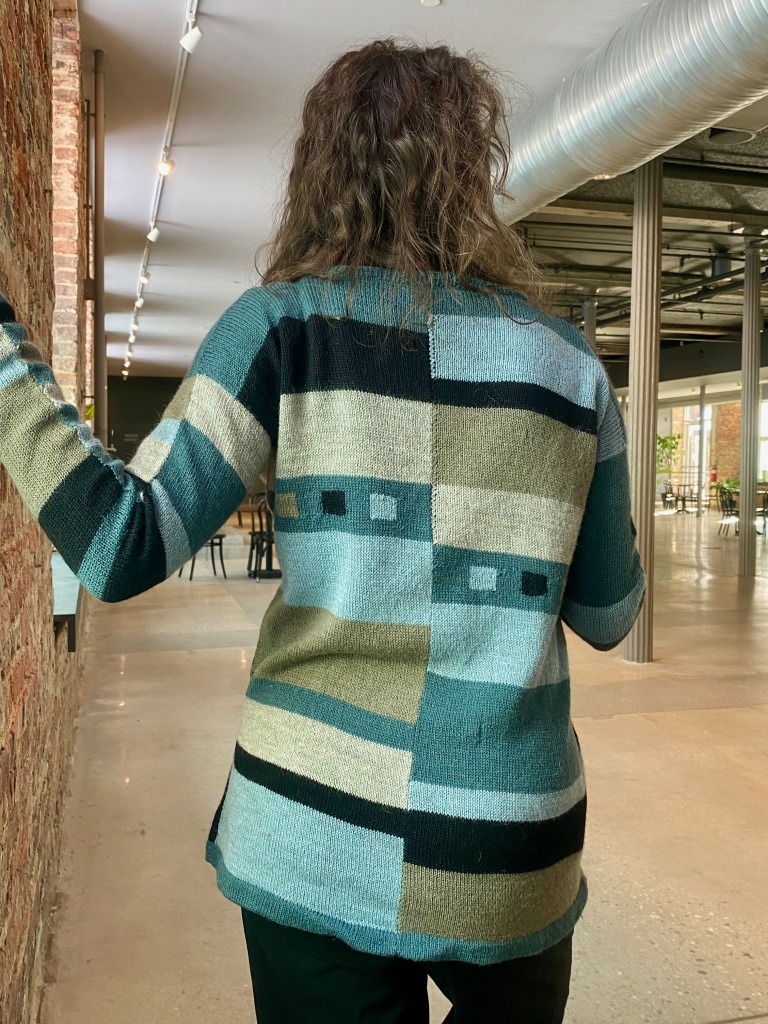 Back view of paneled machine-knit pullover with small intarsia boxes on either side of back
